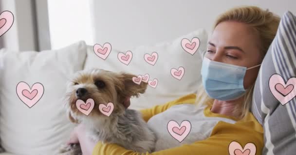 Animación Corazones Moviéndose Sobre Mujer Caucásica Con Máscara Facial Sosteniendo — Vídeo de stock