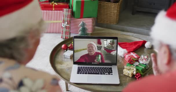 Végzős Fehér Pár Mikulás Sapkával Laptoppal Karácsonyi Videóhívásra Férfiakkal Képernyőn — Stock videók
