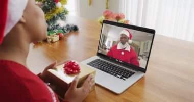 Noel Baba şapkalı Afrikalı bir kadın Noel Baba 'nın ekranında dizüstü bilgisayar kullanıyor. Noel, şenlik ve iletişim teknolojisi.