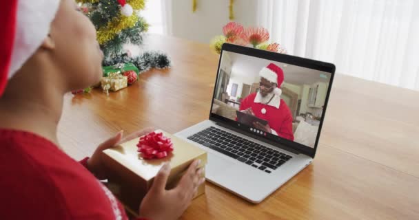 拿着圣塔帽的非洲裔美国女人用笔记本电脑打圣诞视频电话 屏幕上放着圣塔 圣诞节 节日和通信技术 — 图库视频影像