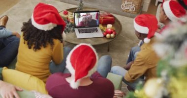 Noel Baba şapkalı çeşitli aileler, ekranda mutlu çiftle Noel görüntülü konuşma yapmak için laptop kullanıyorlar. Noel, şenlik ve iletişim teknolojisi.