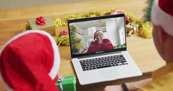 白种人的父亲和儿子戴着桑塔帽 他们用笔记本电脑和屏幕上的女人一起打圣诞视频电话 圣诞节 节日和通信技术 — 图库视频影像