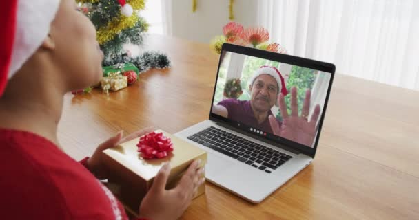 戴大礼帽的非洲裔美国女人用笔记本电脑和男人在屏幕上进行圣诞视频通话 圣诞节 节日和通信技术 — 图库视频影像