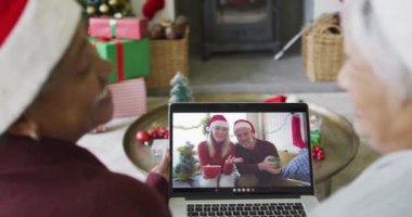 Birçok üst düzey bayan arkadaş, ekranda çift olan bir çiftin yılbaşı görüntüsü için dizüstü bilgisayar kullanıyor. Noel, şenlik ve iletişim teknolojisi.