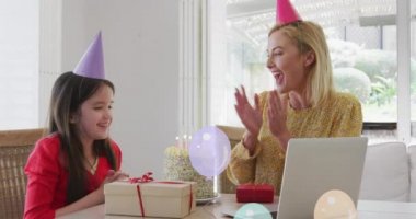 Mutlu bir anne ve kızın doğum günü pastasıyla balon animasyonu dizüstü bilgisayar araması yapıyor. doğum günü, kutlama, parti ve gelenek konsepti dijital olarak oluşturulmuş video.