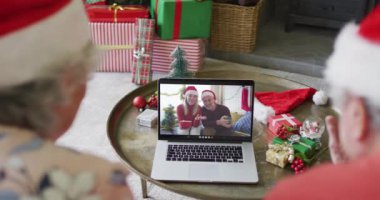 Üst düzey Kafkasyalı çift ekranda mutlu çiftle Noel görüntülü konuşma için dizüstü bilgisayar kullanıyor. Noel, şenlik ve iletişim teknolojisi.