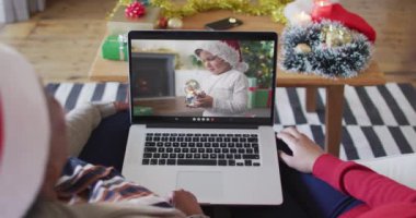 Afrika kökenli Amerikalı anne ve kız. Ekrandaki çocukla yılbaşı videosu için dizüstü bilgisayar kullanıyorlar. Noel, şenlik ve iletişim teknolojisi.