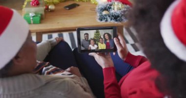 Afrika kökenli Amerikalı anne ve kız. Ekranda aileleriyle birlikte yılbaşı videosu için tablet kullanıyorlar. Noel, şenlik ve iletişim teknolojisi.