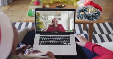 Afrika kökenli Amerikalı anne ve kız. Ekrandaki kadınla yılbaşı videosu için dizüstü bilgisayar kullanıyorlar. Noel, şenlik ve iletişim teknolojisi.