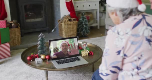 白种人的老年妇女戴着圣诞礼帽 用笔记本电脑和男人在屏幕上进行圣诞视频通话 圣诞节 节日和通信技术 — 图库视频影像