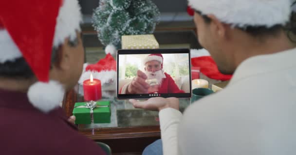 画面上のサンタとクリスマスビデオコールのタブレットを使用してサンタの帽子を持つ実父と息子 クリスマスやお祭りや通信技術は — ストック動画