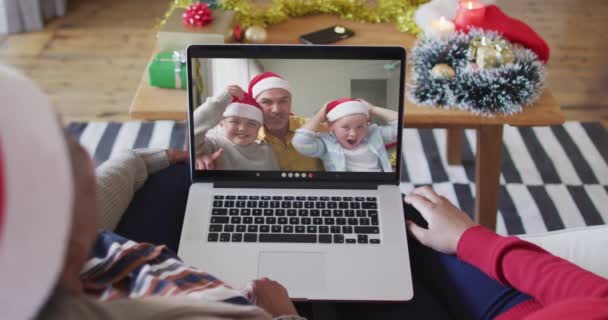 Afro-Amerikaanse moeder en dochter met behulp van laptop voor kerst video gesprek met familie op het scherm — Stockvideo