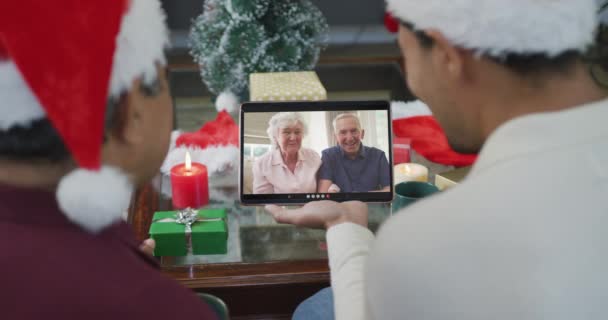 誕生日の父と画面上のカップルとクリスマスビデオコールのタブレットを使用してサンタの帽子を持つ息子 クリスマスやお祭りや通信技術は — ストック動画