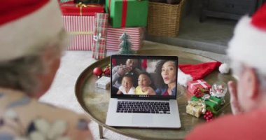 Üst düzey Kafkasyalı çift ekranda mutlu bir aileyle yılbaşı görüntüsü için dizüstü bilgisayar kullanıyor. Noel, şenlik ve iletişim teknolojisi.