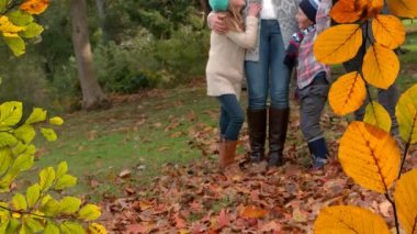 Parktaki mutlu beyaz ailenin üzerine düşen sonbahar yapraklarının animasyonu. sonbahar, sonbahar ve mevsimler dijital olarak üretilen video konsepti.