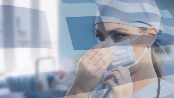 女医生调整面罩上方的希腊国旗动画 数码制作的大肠病毒大流行期间的保健和保护 — 图库视频影像
