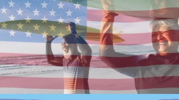 海にサーフボードを運ぶ幸せな高齢者のカップルの上に米国の国旗のアニメーション アメリカの歴史愛国心と独立の概念をデジタルで生成したビデオ — ストック動画