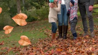 Parktaki mutlu beyaz ailenin üzerine düşen sonbahar yapraklarının animasyonu. sonbahar, sonbahar ve mevsimler dijital olarak üretilen video konsepti.