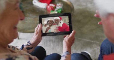 Üst düzey Kafkasyalı çift, mutlu çiftle Noel görüntülü konuşma yapmak için tablet kullanıyor. Noel, şenlik ve iletişim teknolojisi.