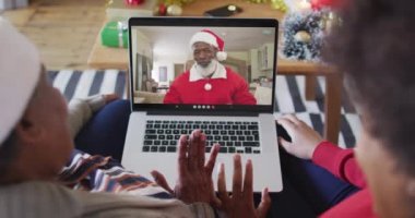 Afrika kökenli Amerikalı anne ve kız Noel 'de ekranda Noel Baba' nın görüntülü araması için laptop kullanıyorlar. Noel, şenlik ve iletişim teknolojisi.