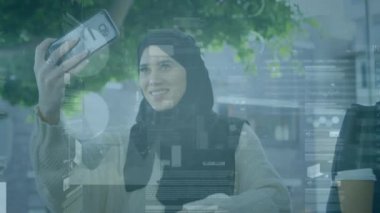Akıllı telefon kullanan tesettürlü kadının istatistik ve veri işleme animasyonu. küresel bağlantılar, teknoloji, veri işleme ve dijital arayüz konsepti dijital olarak oluşturulmuş video.