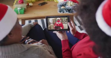 Afrika kökenli Amerikalı anne ve kız Noel 'de ekranda Noel Baba' nın görüntülü araması için tablet kullanıyorlar. Covid 19 salgını sırasında Noel, şenlik ve iletişim teknolojisi.