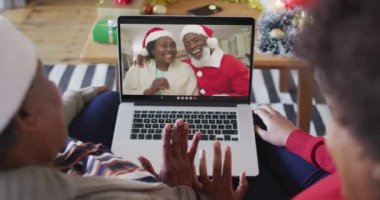 Afrika kökenli Amerikalı anne ve kız. Ekrandaki çiftle yılbaşı videosu için dizüstü bilgisayar kullanıyorlar. Noel, şenlik ve iletişim teknolojisi.