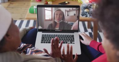 Afrika kökenli Amerikalı anne ve kız. Ekrandaki kadınla yılbaşı videosu için dizüstü bilgisayar kullanıyorlar. Noel, şenlik ve iletişim teknolojisi.