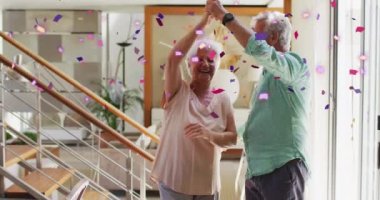 Pembe ve mor konfetilerin evde dans eden Kafkasyalı yaşlı çiftin üzerine düşüşünün animasyonu. emeklilik yaşam tarzı, romantizm ve kutlama konsepti dijital olarak oluşturulmuş video.