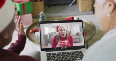 Farklı son sınıf kız arkadaşları, ekranda mutlu bir kadınla yılbaşı görüntüsü için dizüstü bilgisayar kullanıyor. Noel, şenlik ve iletişim teknolojisi.