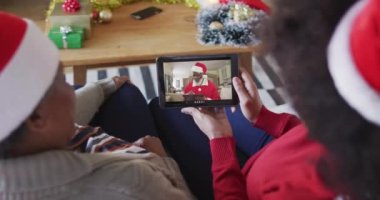 Afrika kökenli Amerikalı anne ve kız Noel 'de ekranda Noel Baba' nın görüntülü araması için tablet kullanıyorlar. Noel, şenlik ve iletişim teknolojisi.