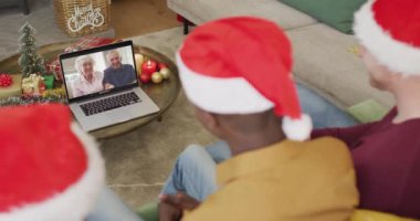 Noel Baba şapkalı çeşitli aileler, ekranda mutlu çiftle Noel görüntülü konuşma yapmak için laptop kullanıyorlar. Noel, şenlik ve iletişim teknolojisi.