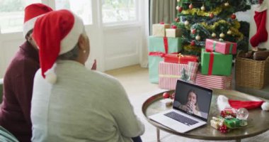 Farklı son sınıf kız arkadaşları, ekranda mutlu bir kadınla yılbaşı görüntüsü için dizüstü bilgisayar kullanıyor. Noel, şenlik ve iletişim teknolojisi.