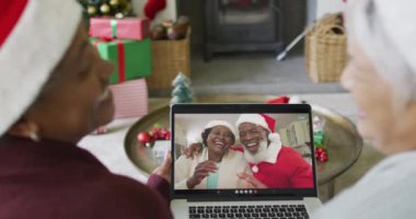 Farklı üst düzey bayan arkadaşlar, mutlu çiftle birlikte ekranda Noel görüntülü konuşma yapmak için dizüstü bilgisayar kullanıyorlar. Noel, şenlik ve iletişim teknolojisi.