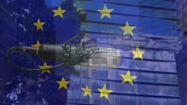 Ofis bloğu ve mikrofon üzerinde Avrupa Birliği bayrağı animasyonu. Avrupa Birliği, politika, ekonomi ve iletişim teknolojisi konsepti dijital olarak oluşturulmuş video.