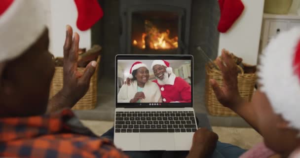 クリスマスのビデオ通話のためのラップトップを使用してサンタの帽子を持つアフリカ系アメリカ人のカップルは 画面上のカップル クリスマスやお祭りや通信技術は — ストック動画