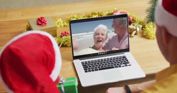 白种人的父亲和儿子戴着桑塔帽 他们用笔记本电脑在屏幕上播放圣诞视频 圣诞节 节日和通信技术 — 图库视频影像