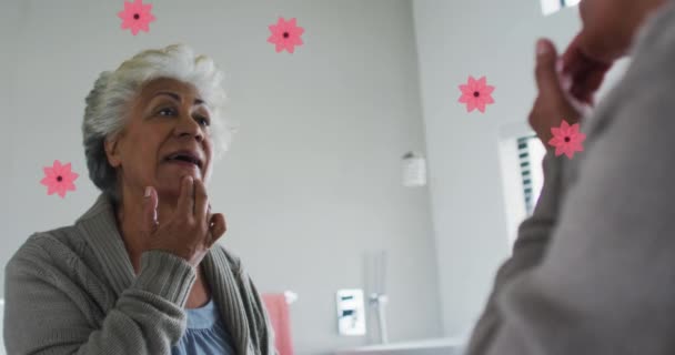 自宅で鏡に映し出す幸せな熟女の上にピンクの花のアニメーション 退職生活と幸福の概念デジタルで生成されたビデオ — ストック動画