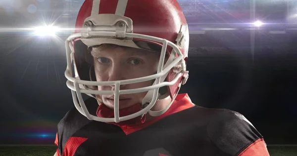 年轻的美国男足球员在灯火辉煌的体育场戴着红色头盔的画像 竞技体育 挑战和保护 — 图库照片