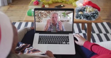 Afrika kökenli Amerikalı anne ve kız. Ekrandaki adamla yılbaşı videosu için dizüstü bilgisayar kullanıyorlar. Noel, şenlik ve iletişim teknolojisi.