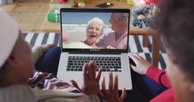 Afrika kökenli Amerikalı anne ve kız. Ekrandaki çiftle yılbaşı videosu için dizüstü bilgisayar kullanıyorlar. Noel, şenlik ve iletişim teknolojisi.