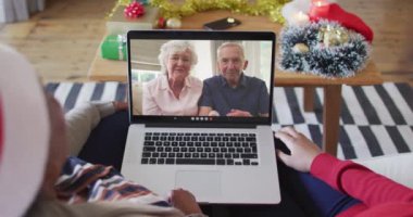 Afrika kökenli Amerikalı anne ve kız. Ekrandaki çiftle yılbaşı videosu için dizüstü bilgisayar kullanıyorlar. Noel, şenlik ve iletişim teknolojisi.