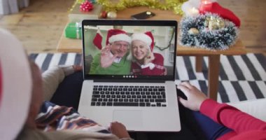 Afrika kökenli Amerikalı anne ve kız. Ekrandaki çiftle yılbaşı videosu için dizüstü bilgisayar kullanıyorlar. Noel, şenlik ve iletişim teknolojisi.