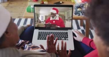 Afrika kökenli Amerikalı anne ve kız Noel 'de ekranda Noel Baba' nın görüntülü araması için laptop kullanıyorlar. Noel, şenlik ve iletişim teknolojisi.