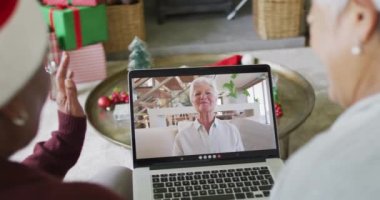 Farklı son sınıf kız arkadaşları, ekranda mutlu bir kadınla yılbaşı görüntüsü için dizüstü bilgisayar kullanıyor. Noel, şenlik ve iletişim teknolojisi.