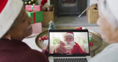 Farklı son sınıf kız arkadaşları Noel 'de ekranda mutlu noel baba videosu için dizüstü bilgisayar kullanıyor. Noel, şenlik ve iletişim teknolojisi.