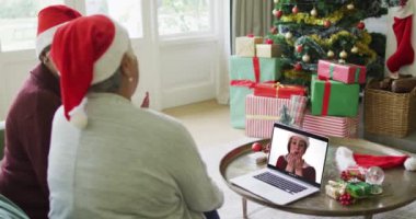 Farklı son sınıf kız arkadaşları, ekranda mutlu bir kadınla yılbaşı görüntüsü için dizüstü bilgisayar kullanıyor. Noel, şenlik ve iletişim teknolojisi.