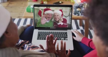 Afrika kökenli Amerikalı anne ve kız. Ekrandaki çiftle yılbaşı videosu için dizüstü bilgisayar kullanıyorlar. Noel, şenlik ve iletişim teknolojisi.