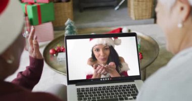 Farklı son sınıf kız arkadaşları, ekranda mutlu bir kadınla yılbaşı görüntüsü için dizüstü bilgisayar kullanıyor. Noel, şenlik ve iletişim teknolojisi.