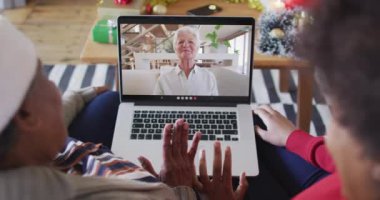 Afrika kökenli Amerikalı anne ve kız. Ekrandaki kadınla yılbaşı videosu için dizüstü bilgisayar kullanıyorlar. Noel, şenlik ve iletişim teknolojisi.